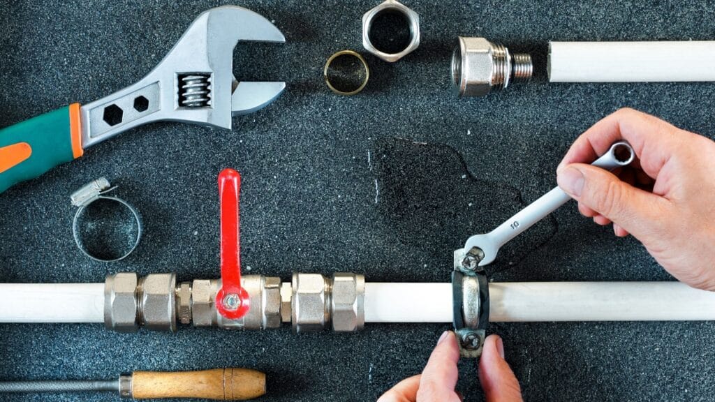 Plumber repairing a pipe valve with an adjustable wrench in Palm Harbor