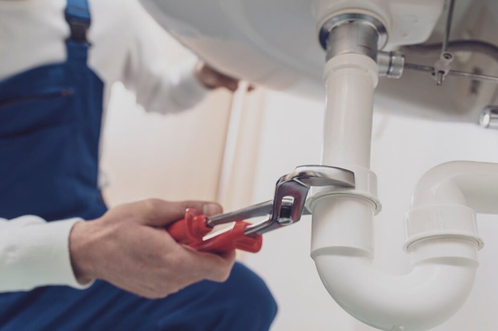 Plumber repairing a white drain pipe beneath a sink in Palm Harbor