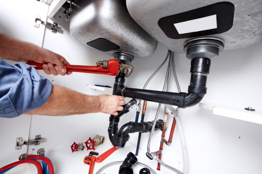 Plumber repairing drain pipes beneath a kitchen sink in Palm Harbor